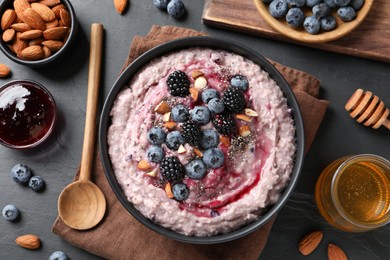 Photo of Tasty oatmeal porridge with toppings served on dark table, flat lay