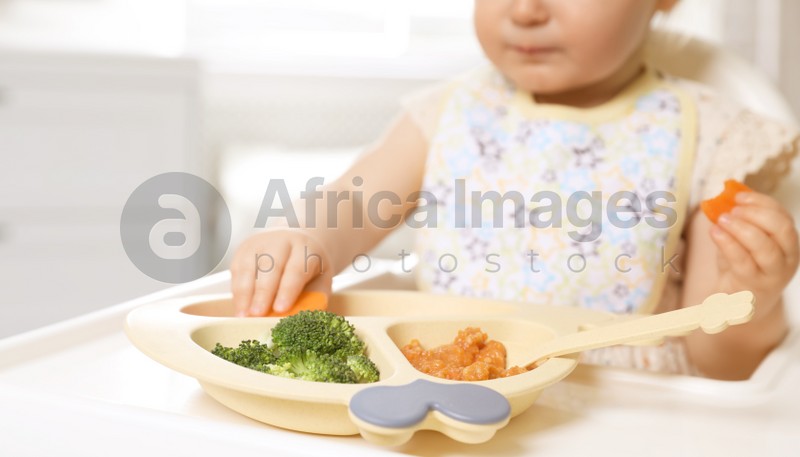 Little baby eating food in high chair, closeup
