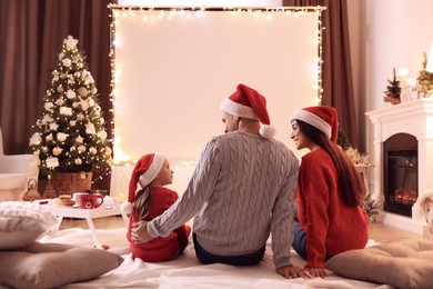 Family watching movie using video projector at home. Cozy Christmas atmosphere