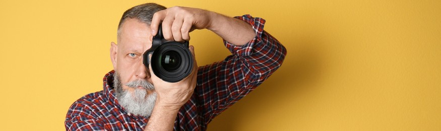 Image of Professional photographer with camera on yellow background, space for text. Banner design