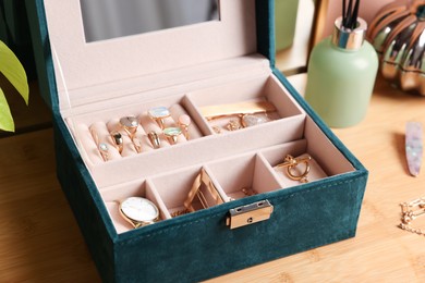 Elegant jewelry box with beautiful bijouterie and expensive wristwatch on wooden table, closeup