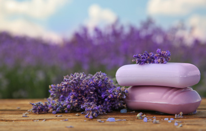 Fresh lavender flowers and soap bars on wooden table outdoors, closeup