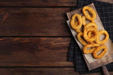 Fried onion rings served on wooden table, top view. Space for text