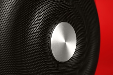 Modern subwoofer on red background, closeup. Powerful audio speaker
