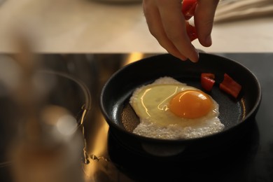Man cooking egg in small frying pan, closeup