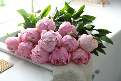 Bouquet of beautiful pink peonies on counter in kitchen