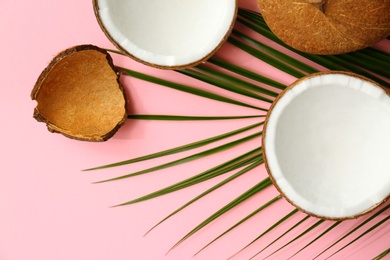 Fresh coconuts and palm leaf on pink background, flat lay