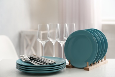 Set of clean dishes, cutlery and wineglasses on white table indoors