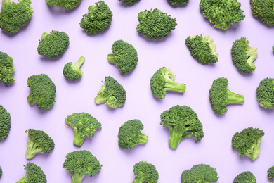 Fresh tasty broccoli on violet background, flat lay