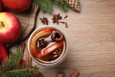 Photo of Hot mulled cider, ingredients and fir branches on wooden table, flat lay. Space for text