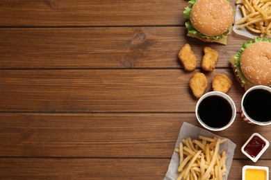 Photo of Flat lay composition with delicious fast food menu on wooden table. Space for text
