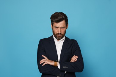 Portrait of offended bearded man on light blue background. Space for text