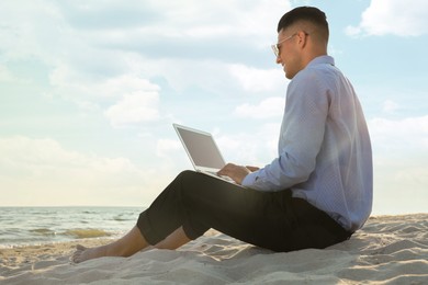 Businessman working with laptop on beach. Business trip