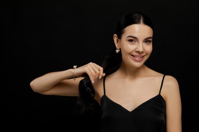 Young woman with elegant pearl jewelry on black background