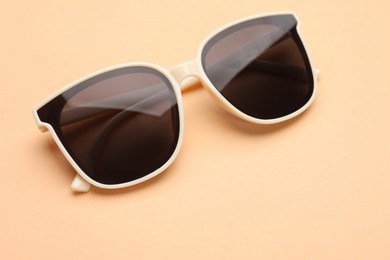 New stylish elegant sunglasses on beige background, closeup