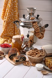 Photo of Traditional Russian samovar and treats on white wooden table