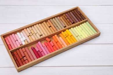 Set of soft pastels in box on white wooden table. Drawing material