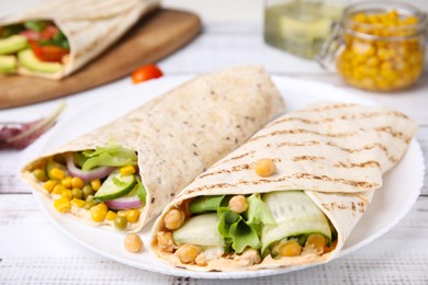 Delicious hummus wraps with vegetables on table, closeup