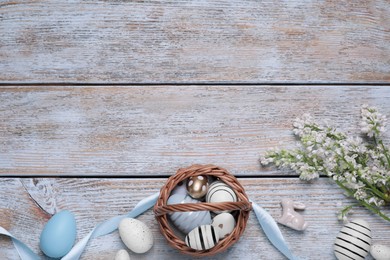 Photo of Flat lay composition with Easter eggs in basket on rustic wooden table. Space for text