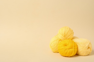 Soft yellow woolen yarns on beige background, space for text