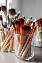 Photo of Set of professional makeup brushes near mirror on grey table