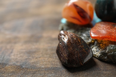 Different beautiful gemstones on wooden table, closeup