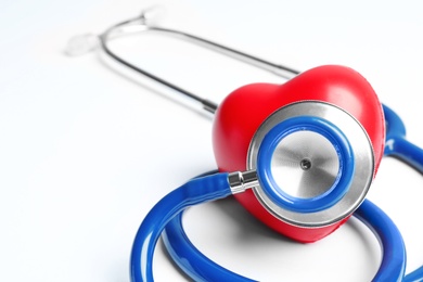 Stethoscope and heart model on light background, closeup. Medical equipment