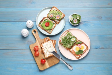 Different delicious sandwiches on light blue wooden table, flat lay