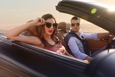 Stylish couple driving luxury convertible car outdoors