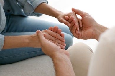 Religious people holding hands and praying together indoors, closeup
