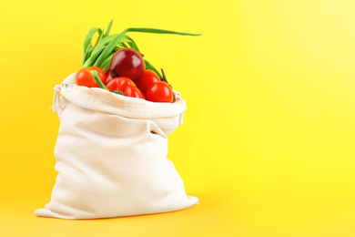 Cotton eco bag with vegetables on yellow background. Space for text