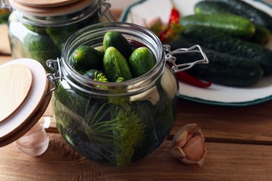 Jar with cucumbers, garlic and dill on wooden table. Pickling recipe
