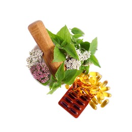Mortar with fresh herbs and pills on white background, top view