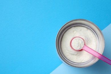Can of powdered infant formula and scoop on color background, top view with space for text. Baby milk