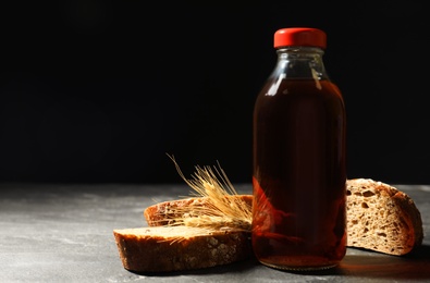 Bottle of delicious fresh kvass, spikelets and bread on grey table. Space for text