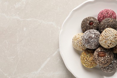 Different delicious vegan candy balls on light grey marble table, top view. Space for text