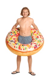 Attractive young man in swimwear with doughnut inflatable ring on white background