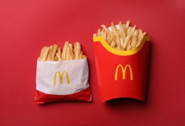 MYKOLAIV, UKRAINE - AUGUST 12, 2021: Small and big portions of McDonald's French fries on red background, flat lay