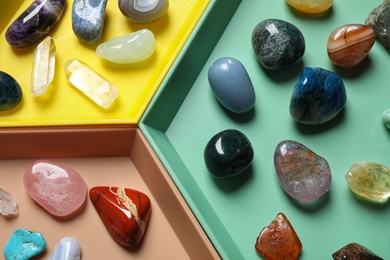 Photo of Plastic tray with different beautiful gemstones as background, top view