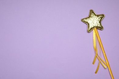 Beautiful golden magic wand on lilac background, top view. Space for text