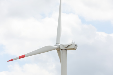 Modern wind turbine against cloudy sky, closeup. Alternative energy source