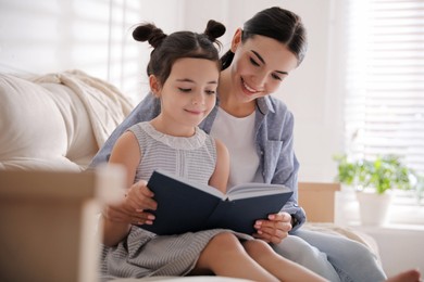 Little girl with mother reading fairy tale in living room