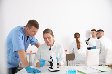 Medical students working with microscope in modern laboratory