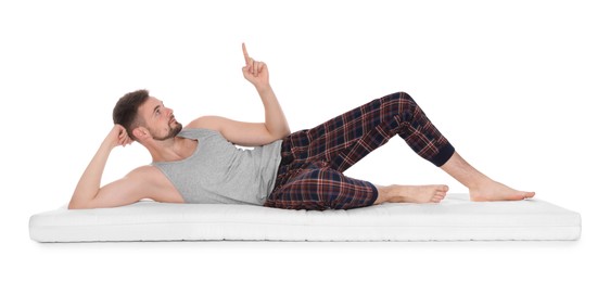 Photo of Man lying on soft mattress and pointing upwards against white background