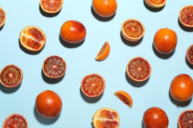 Many ripe sicilian oranges on light blue background, flat lay