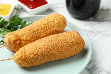 Delicious deep fried corn dogs on white marble table, closeup