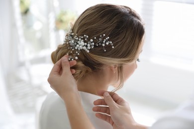 Professional stylist making wedding hairstyle for bride in salon, back view