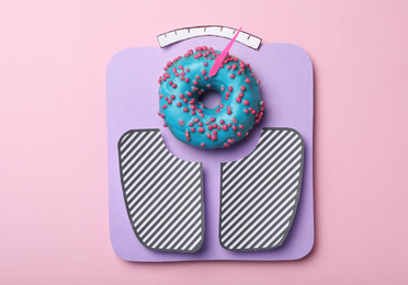 Scales made with donut on pink background, top view