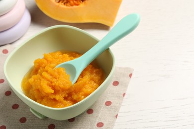 Photo of Baby food. Tasty pumpkin puree on white wooden table, closeup. Space for text