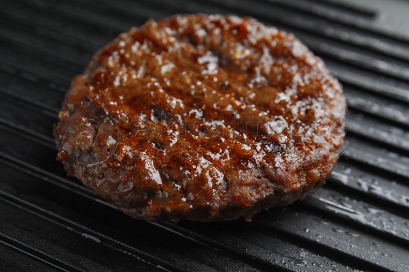 Prepared meat cutlet for burger on grill, closeup